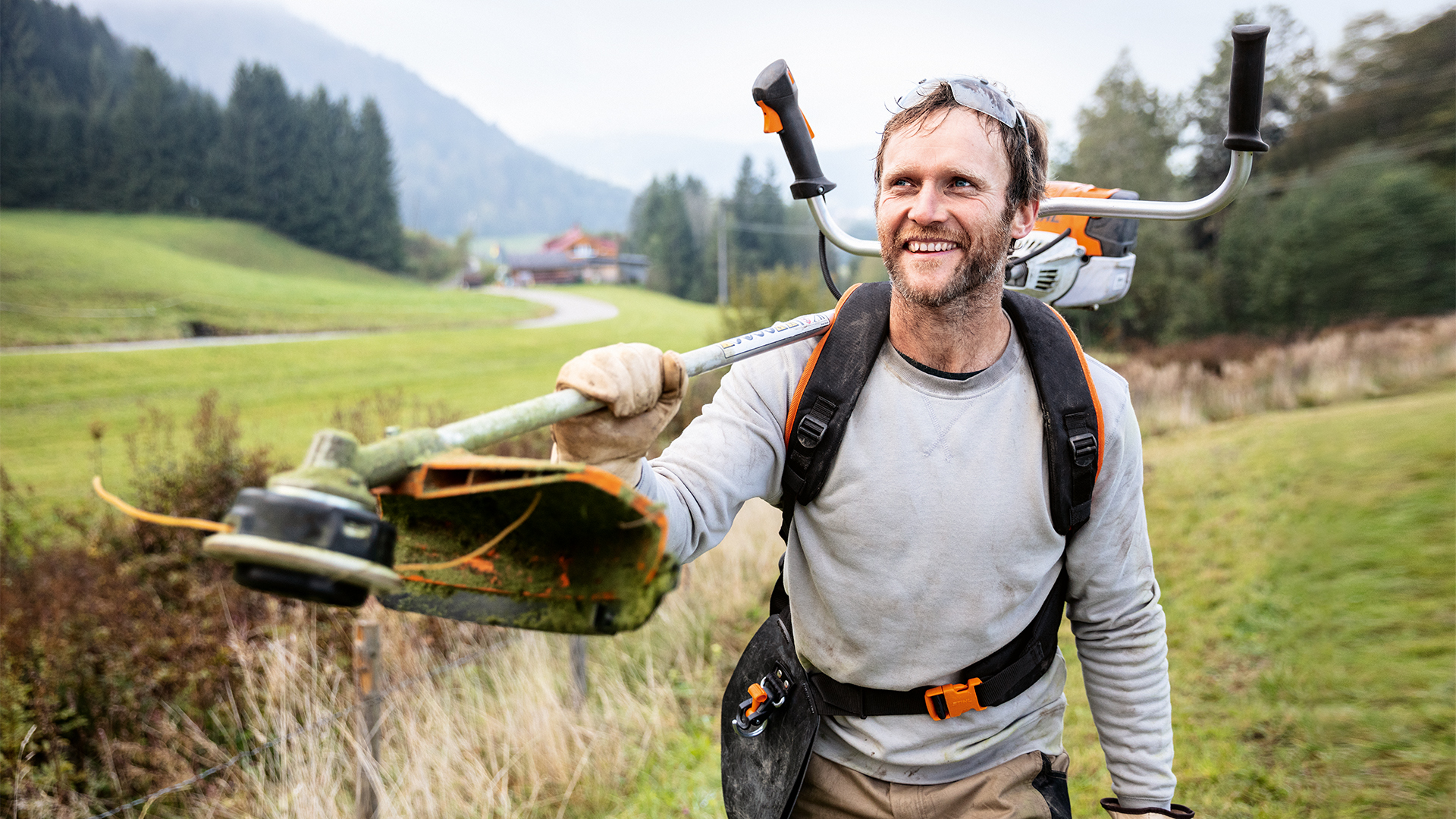 Man met STIHL bosmaaier en universeel harnas Advance PLUS in weide