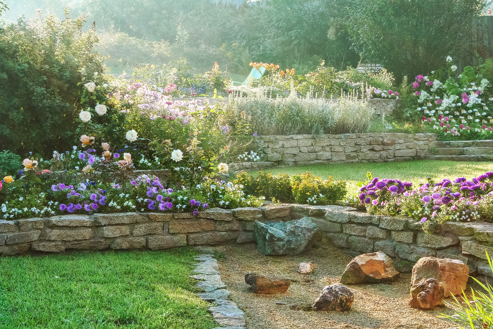 Hellingtuin met stenen muren, bonte bloemen en stukken gras
