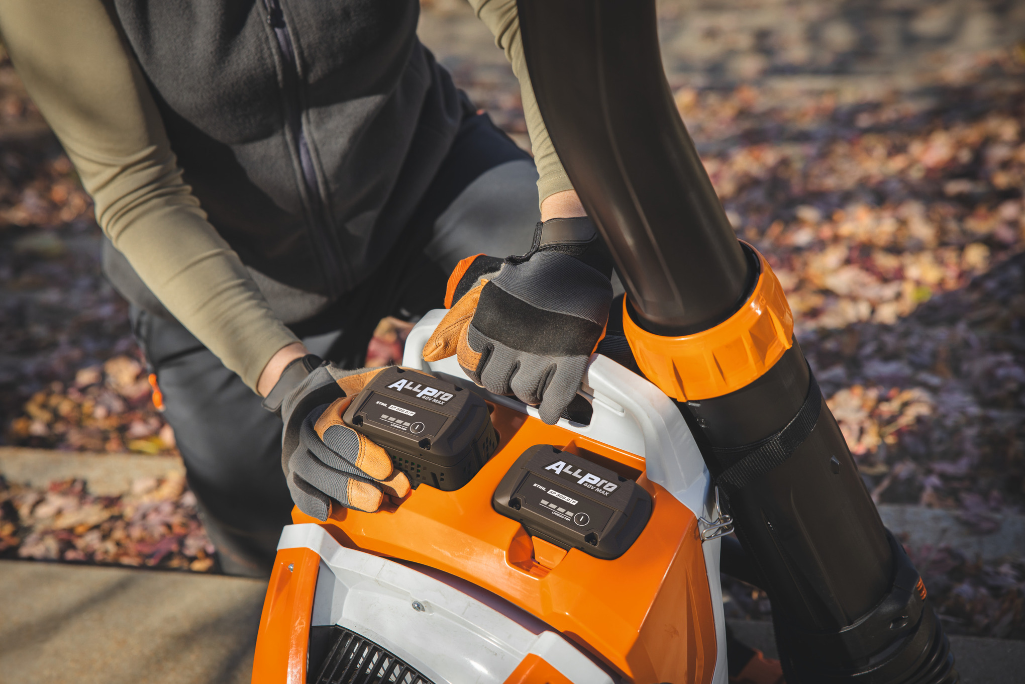 Een professionele tuinarchitect plaatst de tweede STIHL-accu AP 300.0 P in de STIHL-accu-rugzakblazer