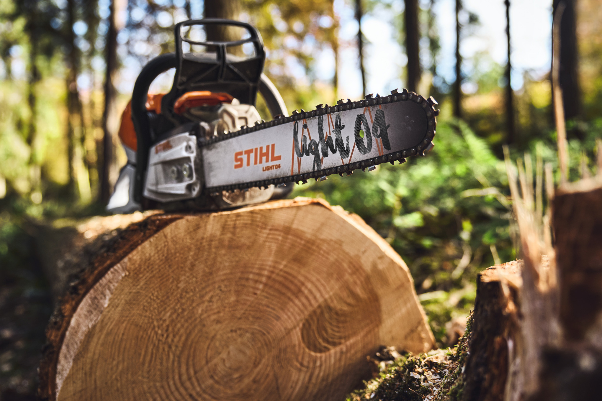 Close-up van een STIHL kettingzaag met Light 04 zaagblad op een boomstronk in het bos