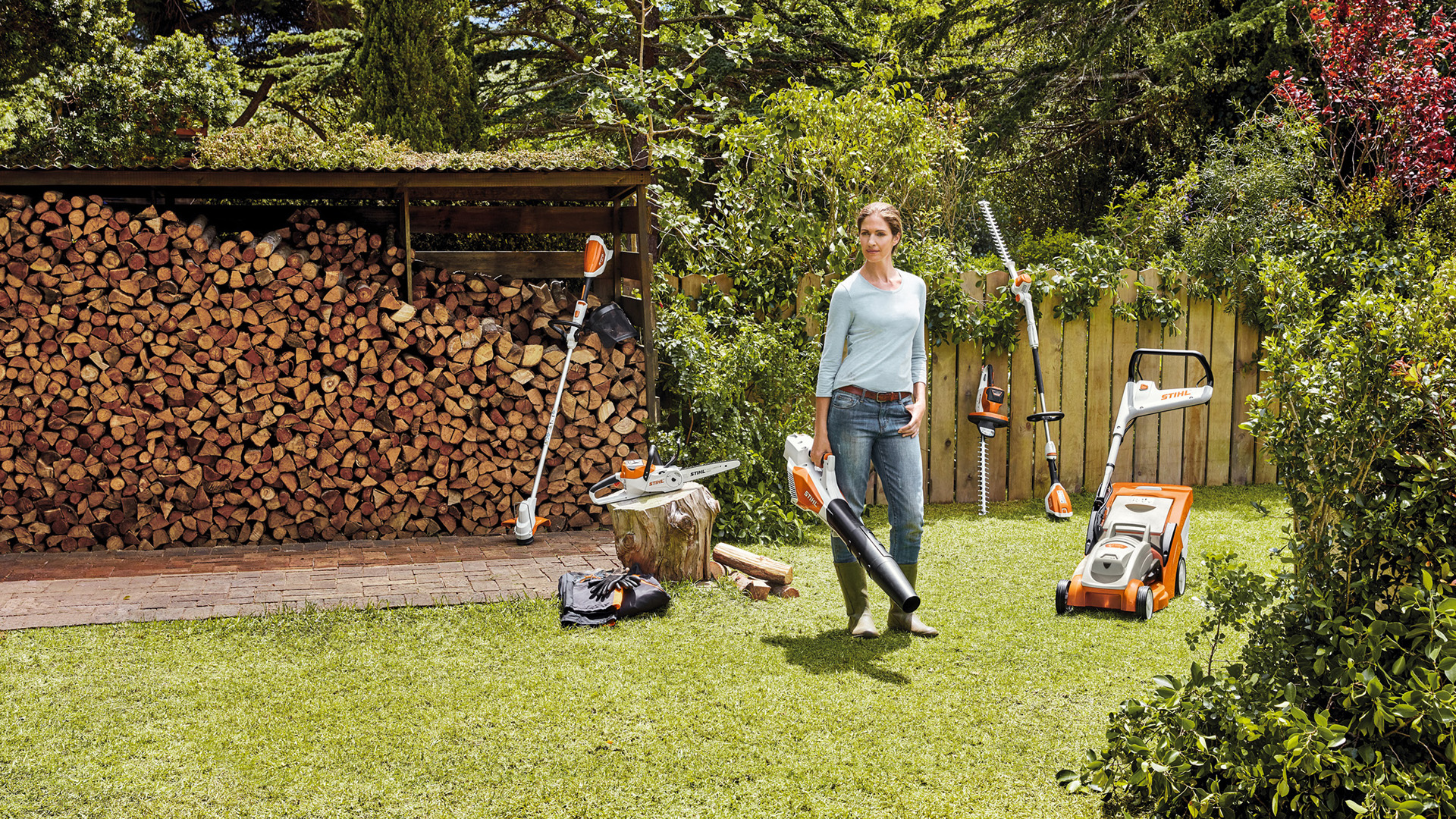 Een vrouw die in een tuin staat met een selectie STIHL AK-systeem snoerloos elektrisch gereedschap