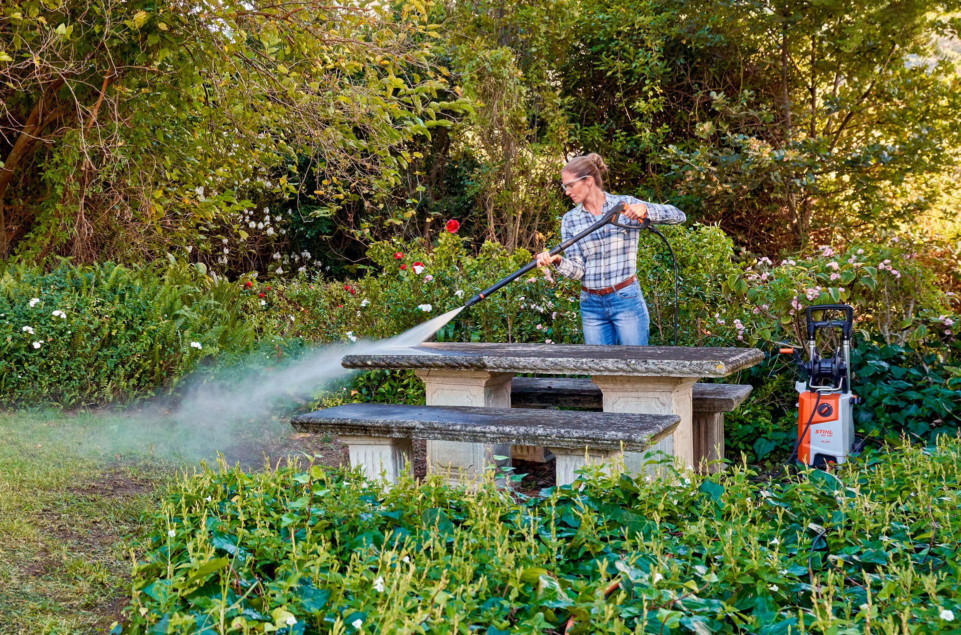 Vrouw tijdens de reiniging van tuinmeubelen met een STIHL hogedrukreiniger