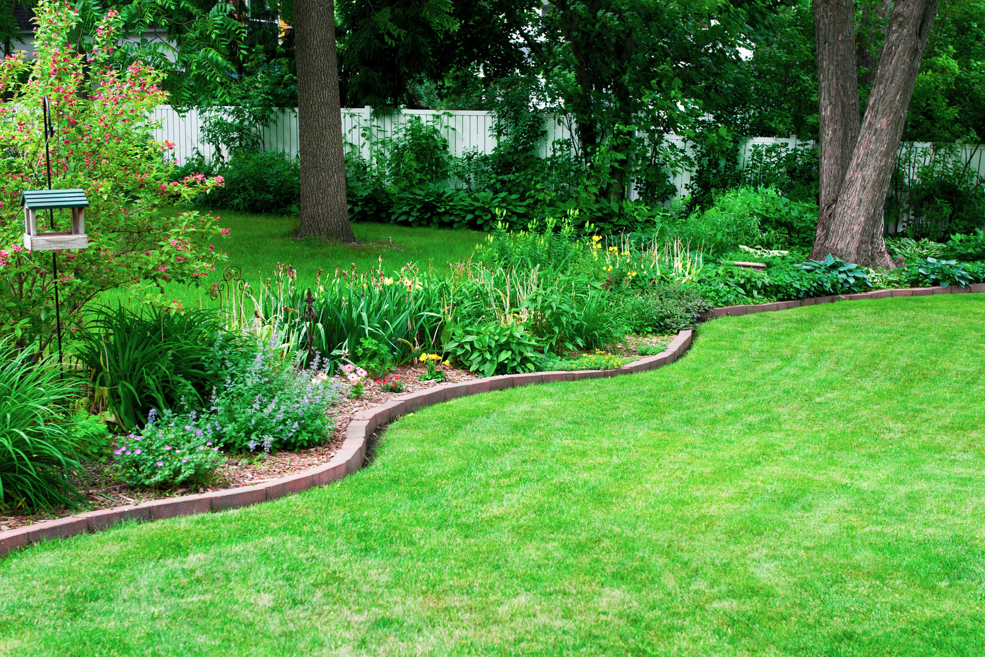 Plantenbed met een zelfgemaakte stenen border op een groen gazon