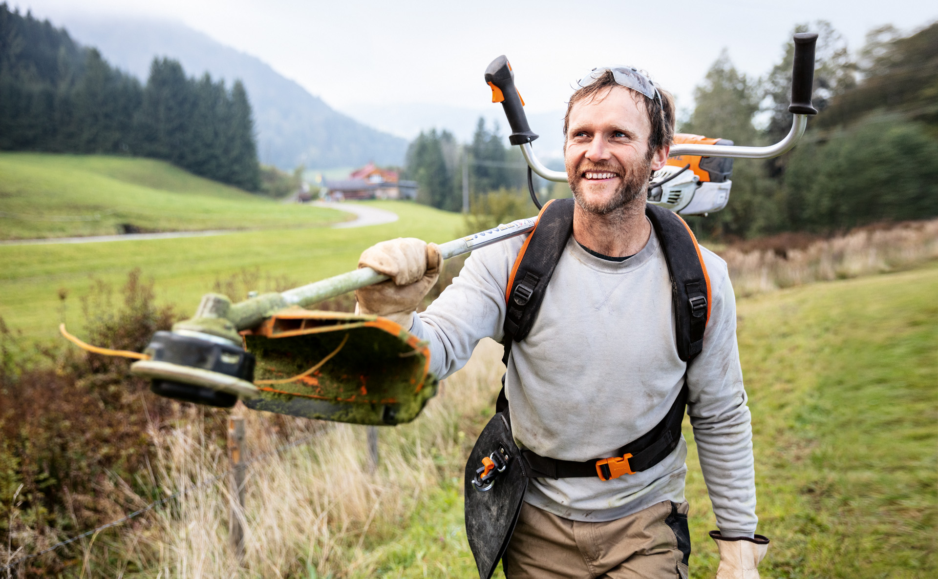 Een man loopt glimlachend over een veld met een STIHL FS 91 bosmaaier