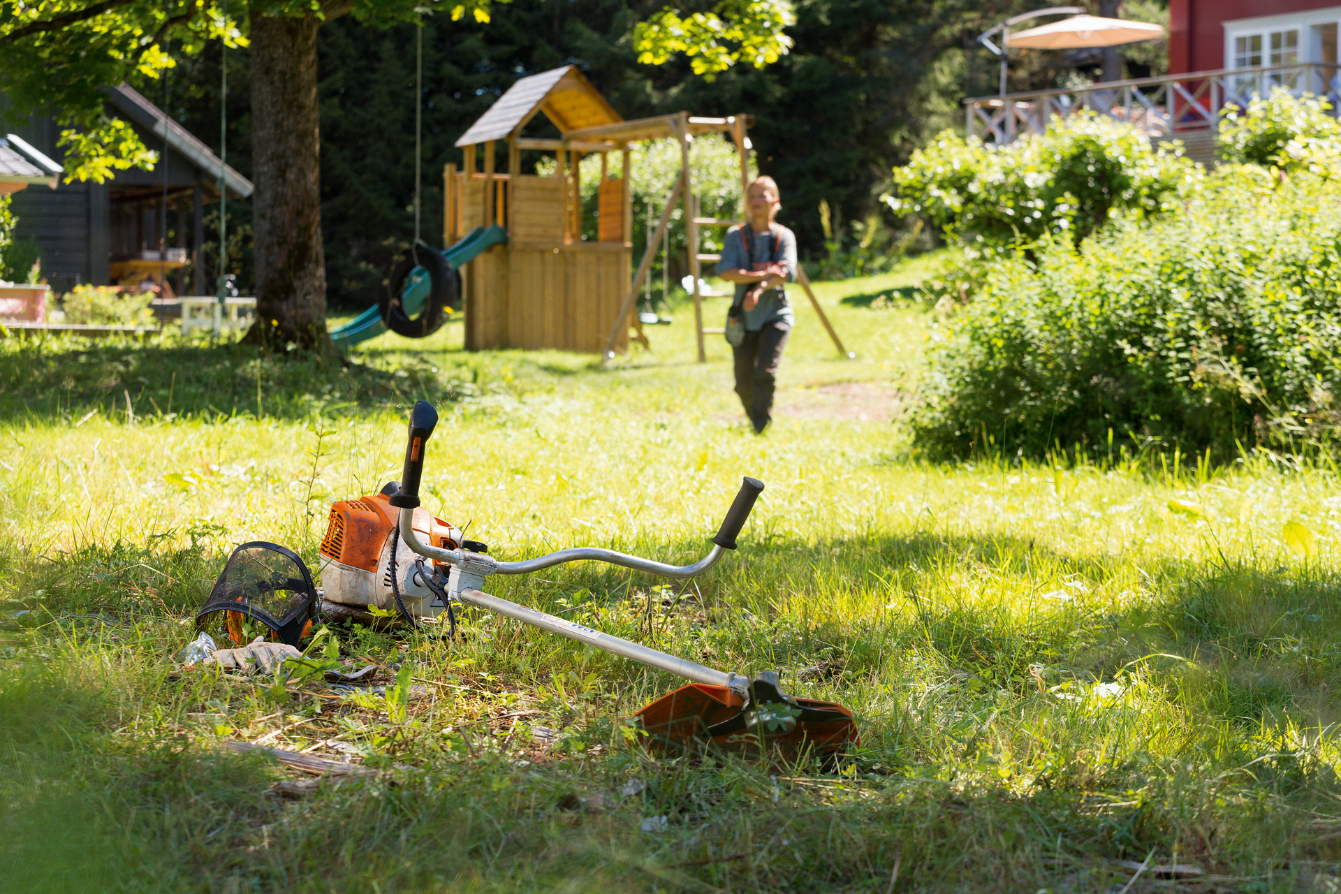 STIHL bosmaaier FS 240 ligt op het gras, op de achtergrond maakt een man zich klaar voor het onderhoud.