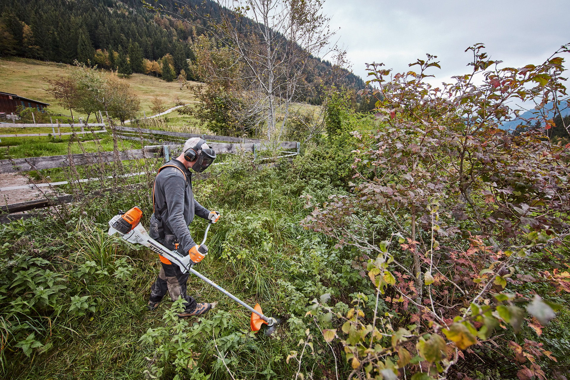 Man in persoonlijke veiligheidsuitrusting maait dicht struikgewas met een STIHL benzinebosmaaier FS 311