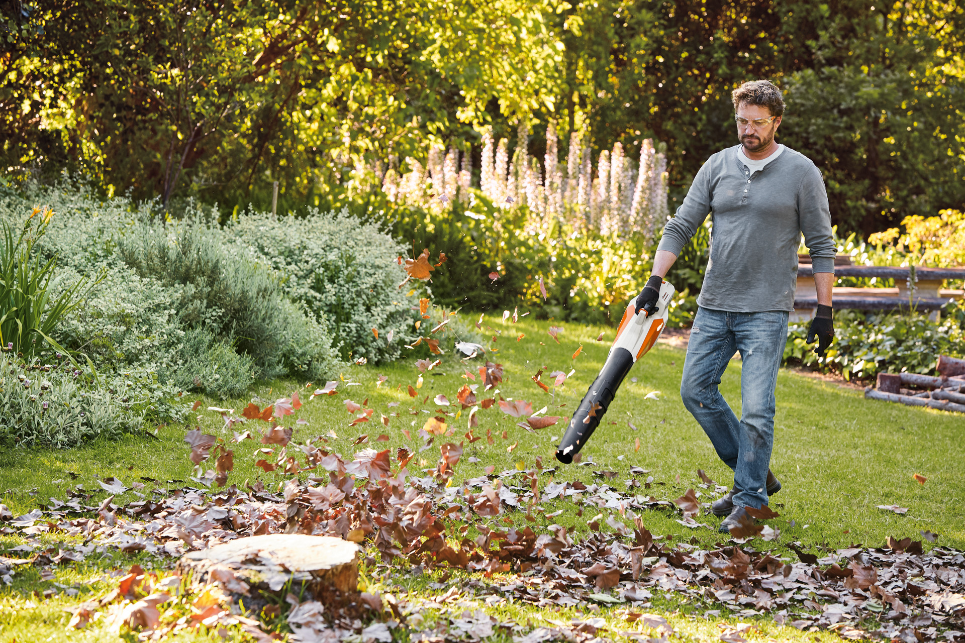 Een man in een tuin gebruikt een STIHL BGA 57 accublazer