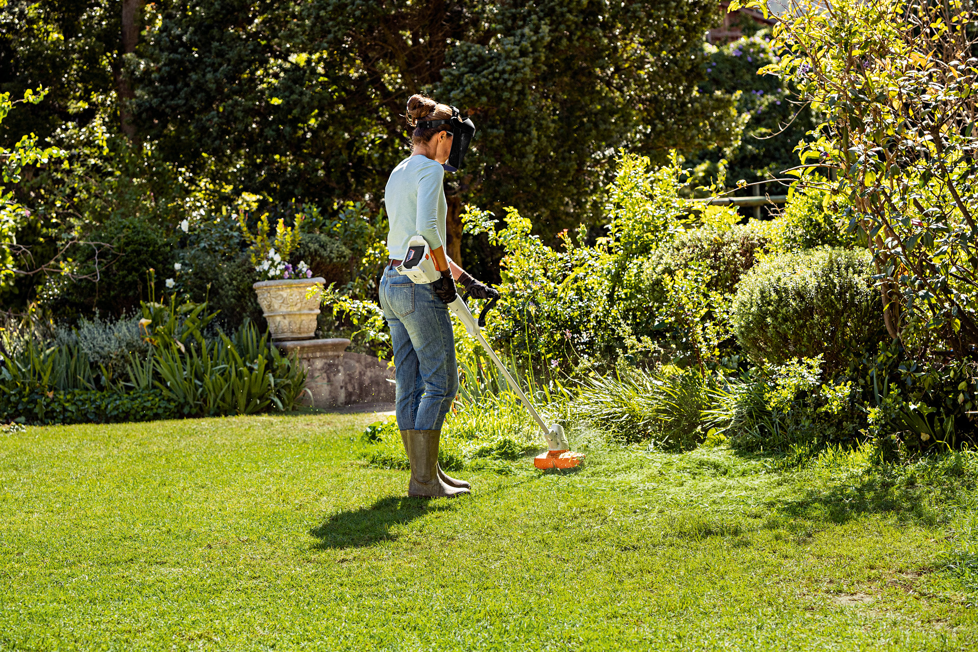 Een vrouw die de rand van een gazon maait met de STIHL FSA 57 grastrimmer