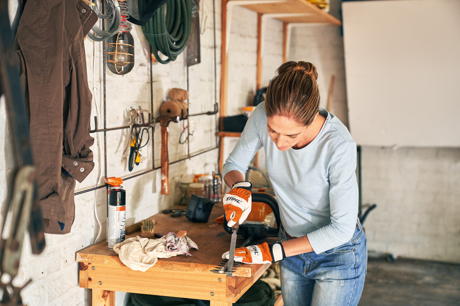 Vrouw slijpt de tanden van een STIHL HSA 56 accu-heggenschaar op een werkbank