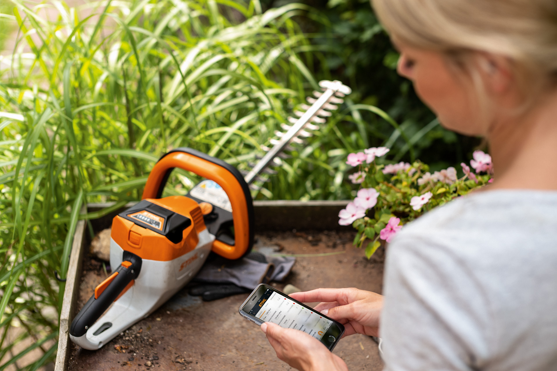 Vrouw registreert haar STIHL heggenschaar met de STIHL app op een smartphone