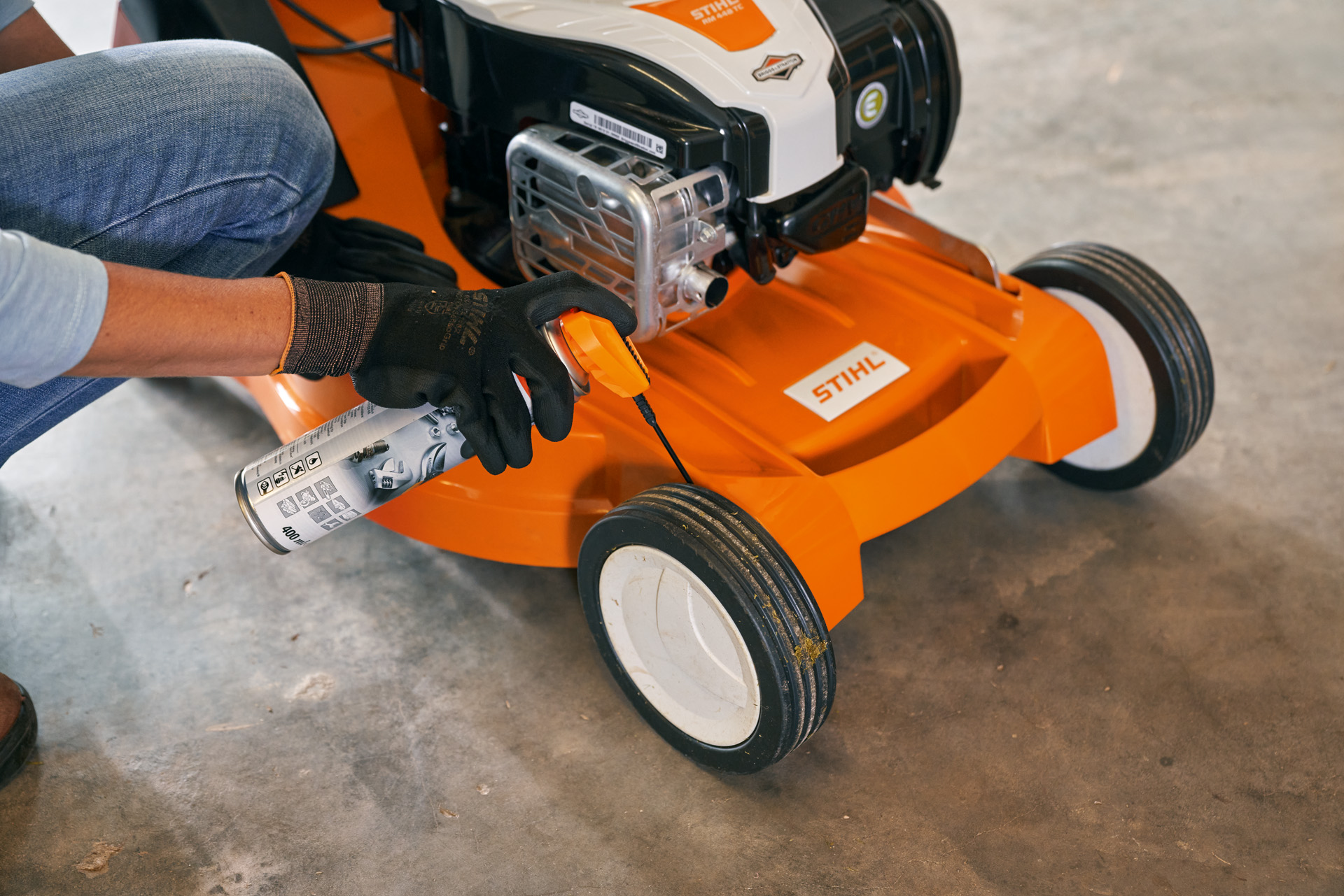 Vrouw bergt haar STIHL RM 448 TC benzinegrasmaaier op in een garage 