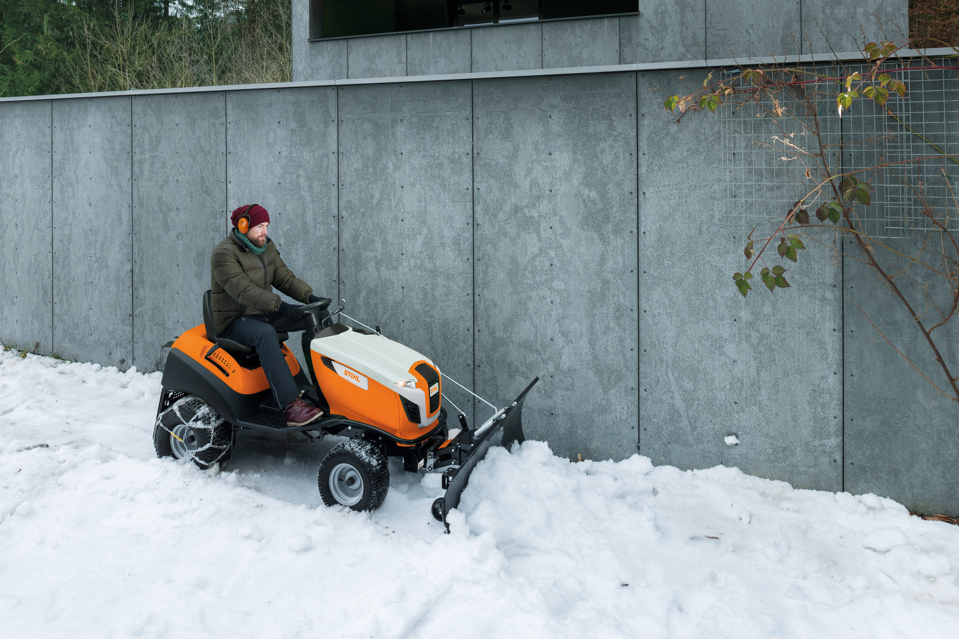 Man ruimt sneeuw met een zitmaaier met sneeuwploeg
