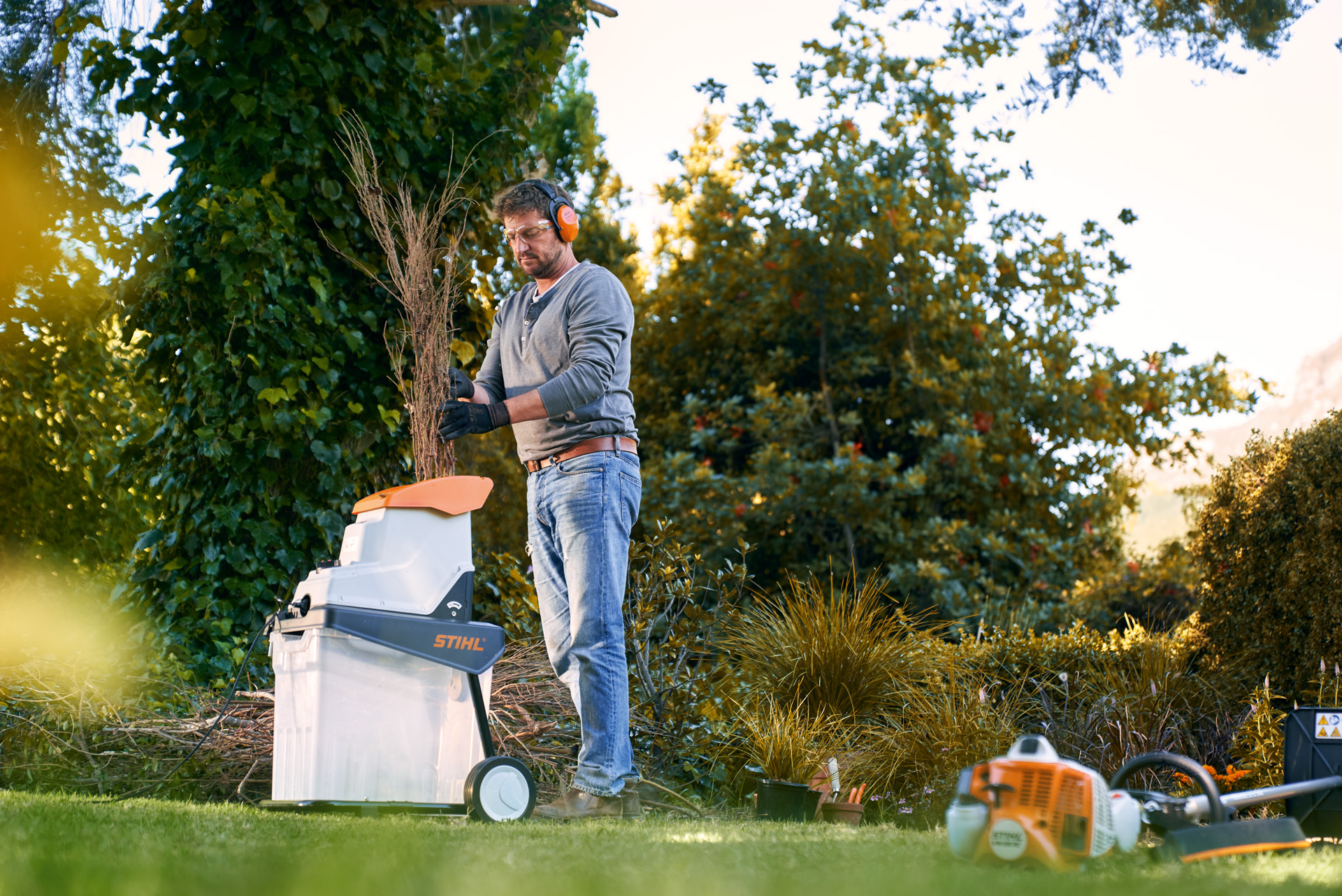 Alt-Text: Man met gehoorbescherming hakselt vóór het composteren takken met een STIHL GHE 140 elektrische hakselaar