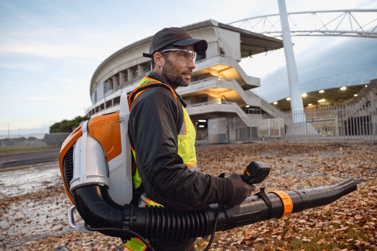 Laat op de avond ruimt iemand bladeren en afval uit een stadion met behulp van de ALLPRO STIHL BRA 600 accu-bladblazer.
