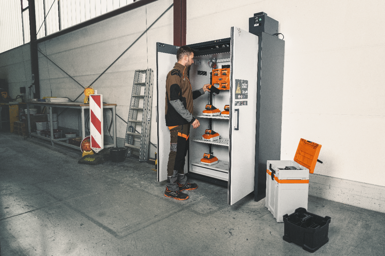 Homme prend une batterie d'une armoire de charge anti-feu
