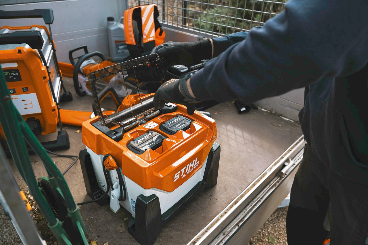  De tuinarchitect plaatst de batterijen in de oplader om ze op te laden.