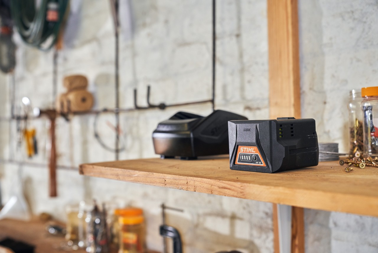 Twee accu's met STIHL accutechnologie liggen op een plank in een werkplaats