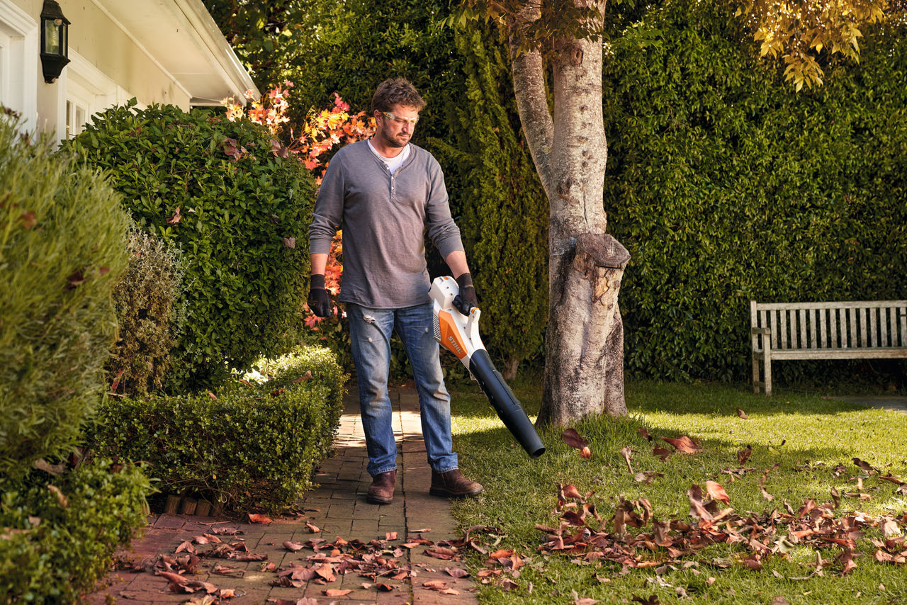 Man verwijdert bladeren van tegels voor het huis met een STIHL BGA 57 accublazer